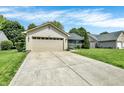 Inviting ranch-style house boasts a long driveway, two-car garage, and lush green lawn under a bright sky at 6838 Cherry Laurel Ln, Fishers, IN 46038