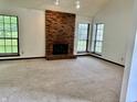 Spacious living room with a brick fireplace, plush carpeting, and large windows at 7042 Colita More Ct, Indianapolis, IN 46254
