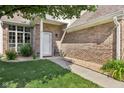 Inviting front entrance with brick facade, a white door, a well-kept lawn, and decorative stone, creating a welcoming entryway at 829 Pioneer Woods Dr, Indianapolis, IN 46224