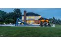 A well-lit backyard featuring a pool with a slide, outdoor bar, and comfortable lounge seating at 15920 Oak Park Ct, Westfield, IN 46074