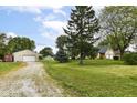 Expansive property with home, long driveway, lush lawn, mature trees, and a detached garage for ample parking and storage at 1624 Riley Rd, Lebanon, IN 46052
