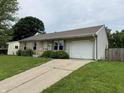 View of the front of the house, highlighting the attached garage and concrete driveway in a well-maintained yard at 1816 Hemlock Ln, Plainfield, IN 46168