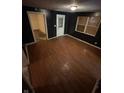 A look at a room with dark walls, light hardwood flooring, and a boarded window at 1902 Orange St, Indianapolis, IN 46203