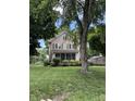 Two-story home with a screened front porch surrounded by greenery and a spacious lawn at 4904 N Washington Blvd, Indianapolis, IN 46205