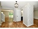 Open entryway with hardwood floors leading to a powder room and living area with modern chandelier at 5759 Columbia S Cir, Greenwood, IN 46142