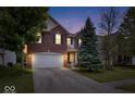 Charming two-story brick home with a well-maintained lawn and mature trees at dusk at 8877 N White Tail Trl, McCordsville, IN 46055