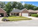 Beautiful brick home boasting a lush green lawn, a cozy front porch, and a convenient two-car garage with landscaping at 9735 Woodsong Ln, Indianapolis, IN 46229