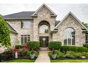 Detailed front exterior of a brick home with elegant landscaping, planters and a welcoming entryway at 1037 Deer Lake Dr, Carmel, IN 46032