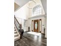 Grand foyer with hardwood floors, staircase, a chandelier, and a large arched window at 1037 Deer Lake Dr, Carmel, IN 46032