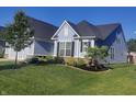 A side view of a blue home featuring black shutters, manicured garden beds and an expansive lawn at 12634 Mustard Seed Ct, Fishers, IN 46038