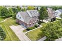 Aerial view of a beautiful brick home with a well-manicured lawn and a long driveway leading to a garage at 13624 Alston Dr, Fishers, IN 46037