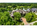 Stunning aerial view of custom home surrounded by mature trees and serene pond at 18 Lost Run Ln, Zionsville, IN 46077
