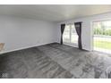 Spacious carpeted living room featuring a large window and sliding glass door at 220 E Tilden Dr, Brownsburg, IN 46112