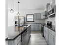 Modern kitchen with stainless steel appliances, sleek gray cabinets, a large island with a dark countertop at 3210 Hovey St, Indianapolis, IN 46218
