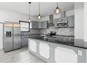 Modern kitchen with stainless steel appliances, gray cabinets, a large island, and pendant lighting, offering plenty of workspace at 3210 Hovey St, Indianapolis, IN 46218
