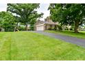 Suburban home with long driveway, basketball hoop, large lawn, and mature trees in the yard at 4585 Abbey Dr, Carmel, IN 46033