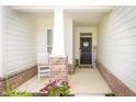 Inviting front porch featuring brick columns, a cozy chair, and a welcoming entrance at 5294 Lndg Pl Ln, Noblesville, IN 46062