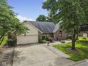 Brick house featuring an attached garage and concrete driveway surrounded by mature trees and landscaping at 5591 Royal Troon Way, Avon, IN 46123