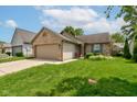 Inviting one-story home featuring a brick facade, attached garage, a vibrant lawn, and cheerful flower beds at 741 Chestnut Ln, Brownsburg, IN 46112