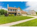 Inviting two-story home with a brick front, lush green lawn, mature trees, and an attached garage at 7710 Samuel Dr, Indianapolis, IN 46259