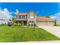 Traditional two-story home boasts a well-maintained lawn, brick facade, and an attached two-car garage at 7710 Samuel Dr, Indianapolis, IN 46259