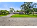 Charming single-story home featuring a lush green lawn, attached garage, and a welcoming front porch at 8025 Meadow Ln, Indianapolis, IN 46227
