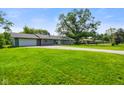 Well-maintained single-story home with an attached garage and spacious front yard with mature trees at 8025 Meadow Ln, Indianapolis, IN 46227