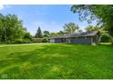 Well-maintained single-story home with an attached garage and spacious front yard with mature trees at 8025 Meadow Ln, Indianapolis, IN 46227
