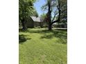 Spacious front yard showcases a classic home nestled among mature trees, providing a picturesque and tranquil setting at 9168 S State Road 9, Flat Rock, IN 47234