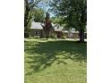 Traditional brick home boasts a lush front lawn, mature trees, and a welcoming facade, offering a serene living environment at 9168 S State Road 9, Flat Rock, IN 47234