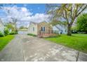 View of home with driveway and detached garage and neutral color scheme at 171 Nursery Rd, Anderson, IN 46012