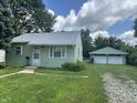 Lovely single story home with green siding, bright white trim, and a detached two car garage at 2473 N Goodlet Ave, Indianapolis, IN 46222