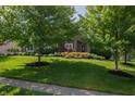 Beautifully landscaped front yard with mature trees providing shade and curb appeal to the brick home at 2901 Hazel Foster Dr, Carmel, IN 46033