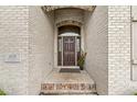 Close-up of a welcoming front door with brick surround, a potted plant, and clear signage at 2920 Bloomsbury S, Greenwood, IN 46143