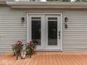 The back porch features double doors with a decorative handle and outdoor lighting with vibrant potted flowers at 3641 Harrison St, Needham, IN 46162