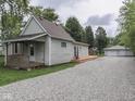 The property showcases a gravel driveway leading to a detached garage and additional parking area at 3641 Harrison St, Needham, IN 46162
