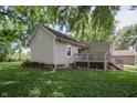 Back exterior view with a wooden deck and lush green surroundings, steps leading down to the yard at 4903 E Naomi St, Indianapolis, IN 46203