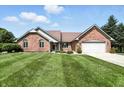 Well maintained brick home with an attached two-car garage and a lush green lawn, offering curb appeal at 8030 5 Points Rd, Indianapolis, IN 46259