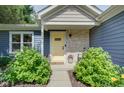 Charming home entrance featuring stone accents, a bright yellow door, and lush landscaping at 9170 Andiron Way, Indianapolis, IN 46250