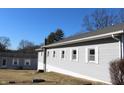 A one-story building with light gray siding and white-framed windows, set against a clear blue sky at 1267 W 750 S, Trafalgar, IN 46181