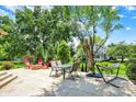 Inviting patio with a dining set, fire pit, and lounge chairs, surrounded by mature trees and lush greenery at 1377 Sedona Dr, Carmel, IN 46032