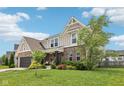 Beautifully landscaped front yard with a brick and siding exterior home with well-manicured lawn, showcasing curb appeal at 1414 W Springhurst Blvd, Greenfield, IN 46140