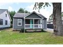 Charming single-story home showcasing a covered porch, gray siding, and a manicured lawn at 1504 Manhattan Ave, Indianapolis, IN 46241