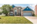 Charming two-story home with a well-manicured lawn, a gray two-car garage and brick facade at 1521 Midnight Pass, Brownsburg, IN 46112