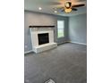 Cozy living room features plush gray carpet, a painted brick fireplace, and natural light at 19236 Fox Chase Dr, Noblesville, IN 46062