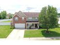 Two-story brick home features a well-manicured lawn and an attached two-car garage at 5063 Haywood Ln, Plainfield, IN 46168