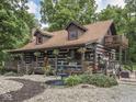 Charming log home with wraparound porch, second story balcony, and lovely landscaping with mature trees at 5240 W 400 N, Fairland, IN 46126