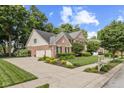 Expansive corner lot with a brick two-story home featuring a three car garage, a basketball hoop, and manicured landscaping at 5997 Hollythorn Pl, Carmel, IN 46033