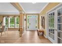 Elegant foyer featuring hardwood floors, decorative columns, and a view of the front yard through a large window at 5997 Hollythorn Pl, Carmel, IN 46033