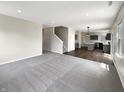 Spacious living room with plush carpeting, open layout, and view of modern kitchen at 6933 Sonora Blvd, Clermont, IN 46234
